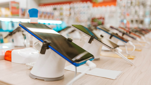 Mobile phones stand on stands for sale to customers who use mobile communications, made a beautiful merchandising, wooden table top in the store of mobile phones and phones, sales of digital equipment