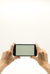 Woman's hands  holds in front of her a black phone with white screen on white background.