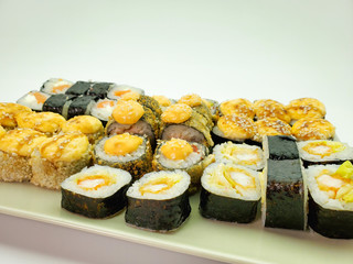 Sushi rolls on a light rectangular plate, isolated background.