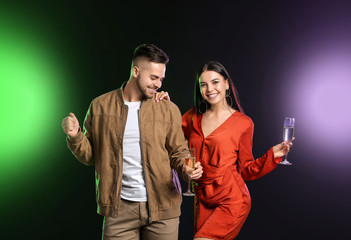 Happy couple with glasses of champagne on dark background