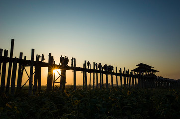 Obraz premium Silhouette of U bein bridge at sunset with sunrays shining under bridge in Amarapura, Mandalay, Myanmar