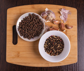 Black pepper in a plate and garlic on the table.
