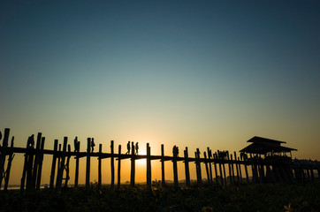 Obraz premium Silhouette of U bein bridge at sunset with sunrays shining under bridge in Amarapura, Mandalay, Myanmar