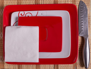 Plates, napkins, and a knife on the table.