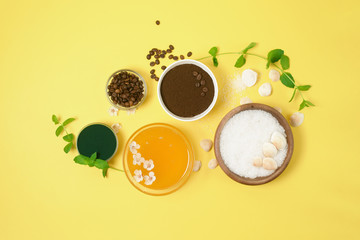 natural organic ingredients-sea salt, coffee scrub, honey and a hard body brush on a yellow background. home skin care for cellulite. concept of skin care, home Spa. the view from the top.