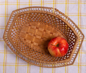 A red Apple in a basket on the table. Drops of water glisten on the Apple.