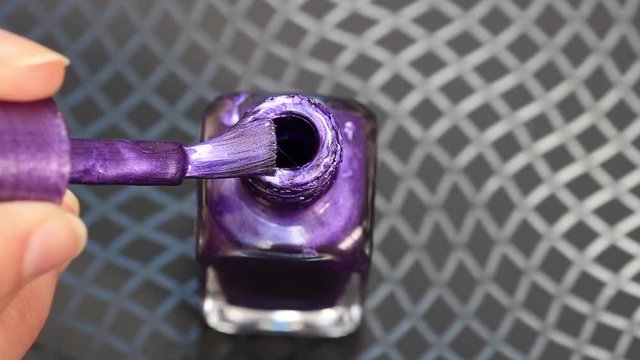 Purple glitter nail polish with brush in bottle