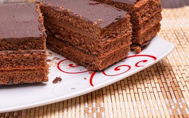 Sliced chocolate cake on a plate on the table. Close up.