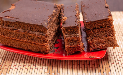 Sliced chocolate cake on a plate on the table. Close up.