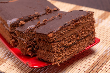 Sliced chocolate cake on a plate on the table. Close up.