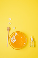 honey in a plate with a spoon and cherry flowers on a pink background. natural ingredient for skin care