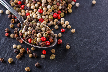 mix of peppercorns on a dark stone background