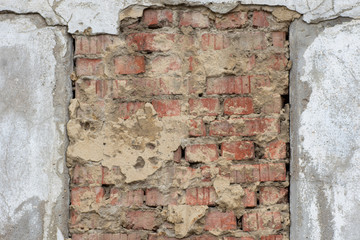 Old gray decorative stucco of the facade of the house in natural scratches and scuffs in the middle of an old orange brickwork. Decorative background, wallpaper, lining