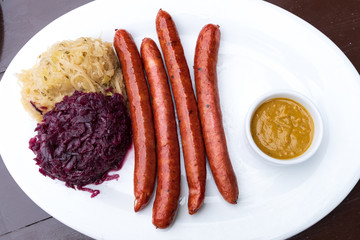 classic German snacks, sausages with mustard cabbage and bagel on a white plate
