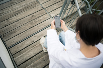 Frau in Laborkleidung macht Pause mit Mundschutz
