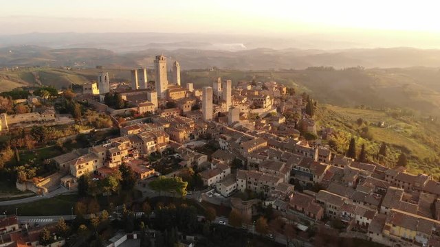 Aerial video from a drone view of the famous towers of San Gimignano, the pearl of Tuscany, surrounded by the Tuscan hills at dawn, the medieval Italian city of skyscrapers, a UNESCO heritage site