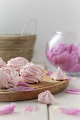 Pink marshmallow and pink peony on a white wooden table