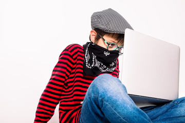 Cute boy with glasses on a white background with a mask using a laptop indoors