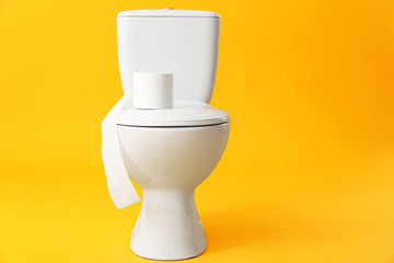 Toilet bowl with roll of paper on color background