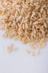 raw brown rice on white acrylic background