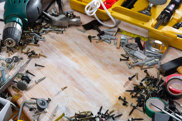 Various screws, bolts, tools on a wooden table. Space for text