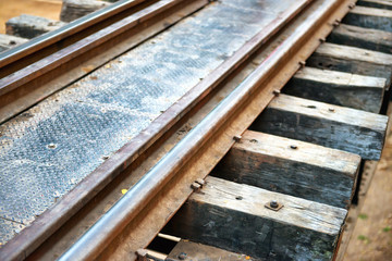 Fototapeta na wymiar Rail track with wooden sleepers and rusty rails at old railway bridge 