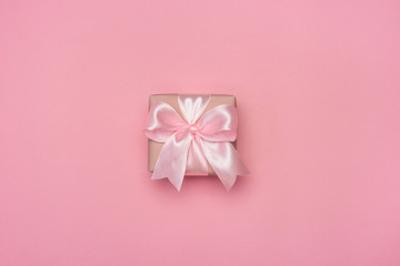 Gift box with pink ribbon bow isolated on pastel pink background. Present for Women's day, Birthday or Mothers Day. Best gift for women concept. Top view flat lay.