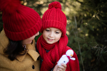 mother and a child candid moments hugging cuddling  playng outside outdoor park wearing red hats in cold autumn fall winter season 