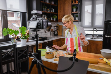 Elderly woman baking for her online streaming cooking channel. Older woman vlogging