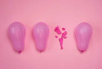 One popped balloon among other whole pink balloons on pink background. Burnout or being under...