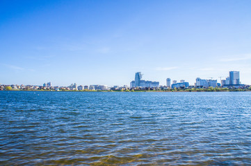 Fototapeta premium Beautiful urban lake with buildings and skyscrapers on the horizon