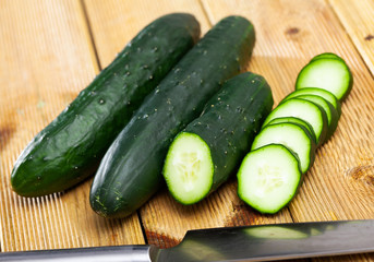 Cut fresh green cucumbers on wooden background, nobody