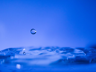 Water drop creating waves ripples and air borne water droplet