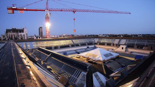 Une grue de chantier reprend le travail au lever du jour sur les toits de la vielle ville de Nantes 