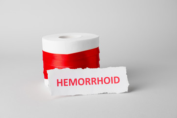 Toilet paper with red ribbon on light background. Hemorrhoids concept