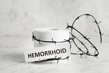 Toilet paper with barbed wire on light background. Hemorrhoids concept