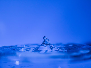 Water drop creating waves ripples and air borne water droplet