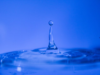 Water drop creating waves ripples and air borne water droplet