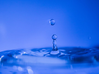 Fototapeta na wymiar Water drop creating waves ripples and air borne water droplet