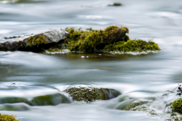 Fototapeta na wymiar Mossy stone in an forest river , Long exposure