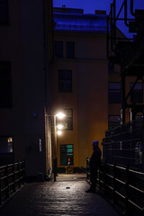 Fototapeta na wymiar Norrkoping, Sweden A man stands at night in the old and renovated industrial mill section of town.