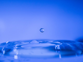 Water drop creating waves ripples and air borne water droplet