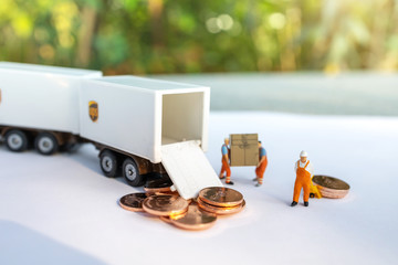 Miniature people:  Worker loading box and coins  to truck container. Shipping and online delivery service concept.