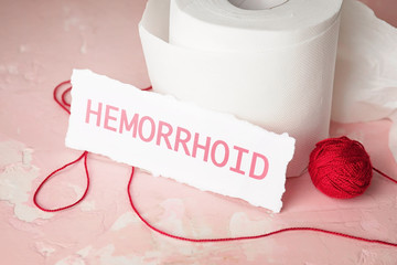 Toilet paper with red thread on color table. Hemorrhoids concept