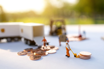 Miniature people:  Worker loading box and coins  to truck container. Shipping and online delivery service concept.