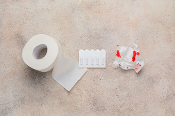 Toilet paper and hemorrhoidal suppositories on light background