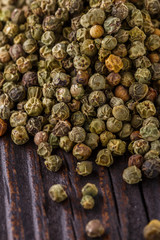 green peppercorns in wooden scoop on rustic background