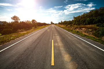 Empty asphalt road through the green field and clouds on blue sky in summer day.