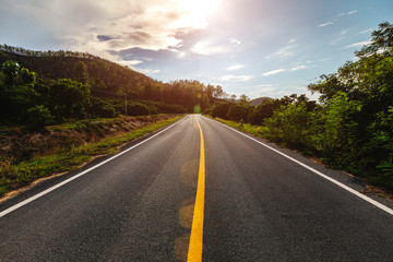 Fototapeta premium Empty asphalt road through the green field and clouds on blue sky in summer day.