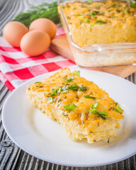 Delicious potato casserole with egg and cheese on a gray wooden background